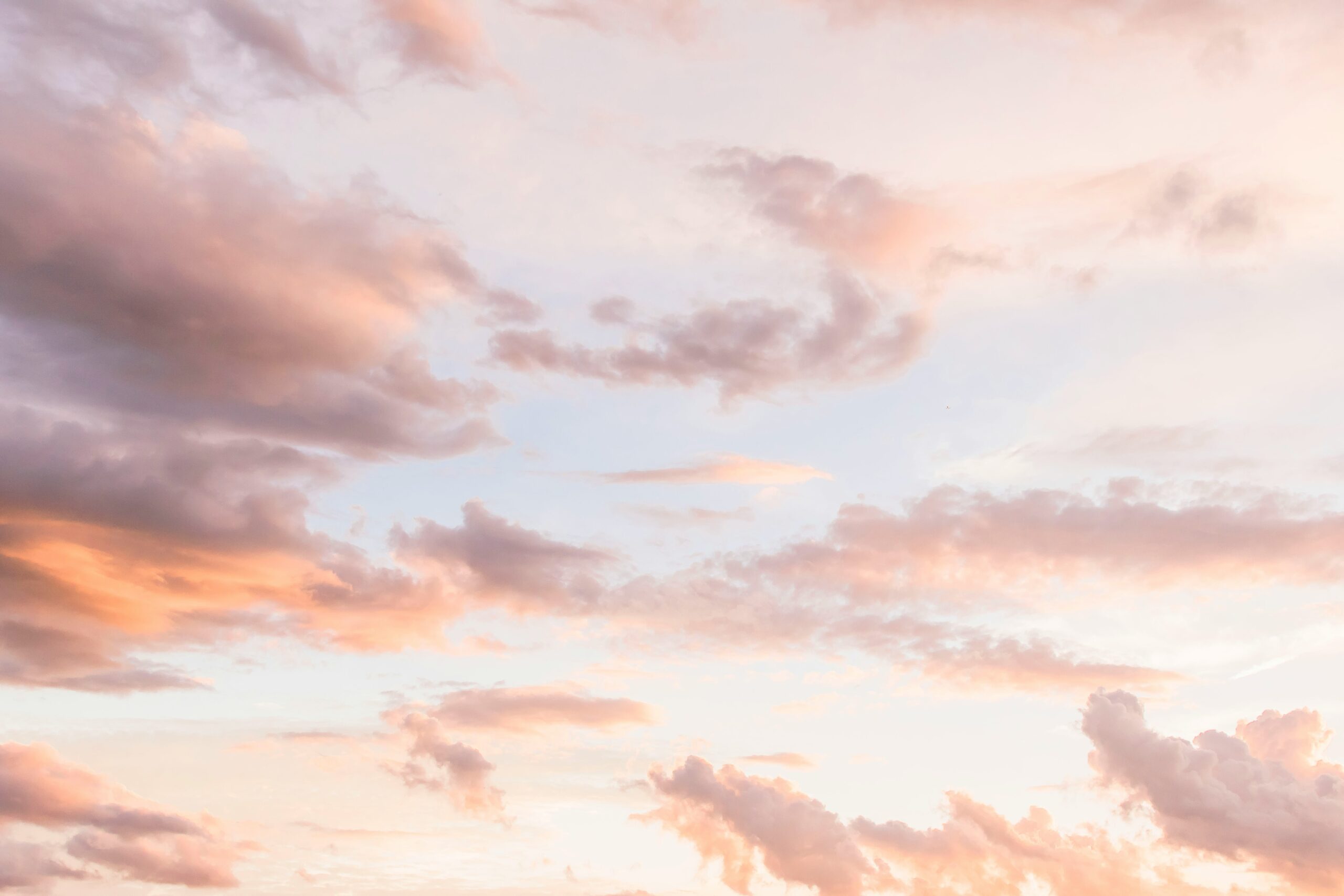 Look up. Beautiful clouds reflecting the light of the sun in pastel colours.