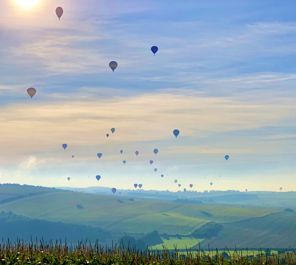 Hot air balloons float calmly over the English coutryside.