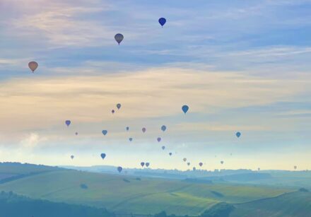 Hot air balloons float calmly over the English coutryside.
