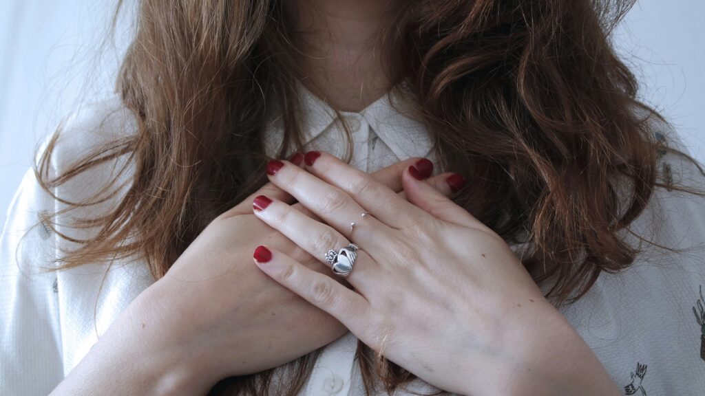 Close up of a woman with hands held over her heart.