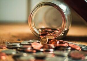 Money spills out of a jar and onto a table.