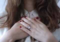 Close up of a woman with hands held over her heart.